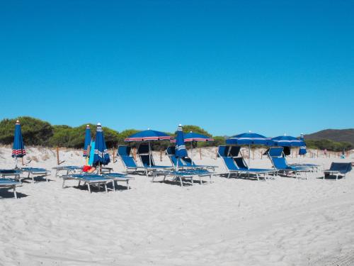 a bunch of chairs and umbrellas on a beach at Apartment Resi by Interhome in Tanaunella