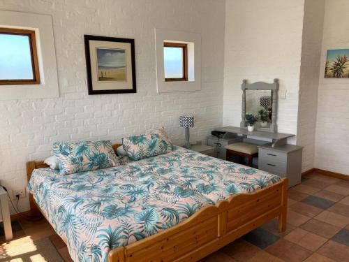 a bedroom with a bed and a desk and a mirror at Net Net Holiday Home in Witsand