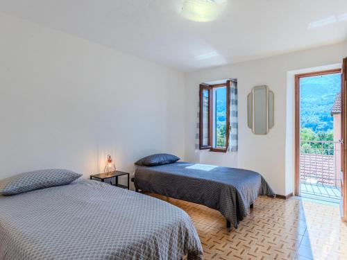 two beds in a room with a window at Holiday Home Papaveri e Papere by Interhome in Piano Porlezza