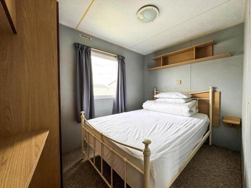 a bedroom with a bed with white sheets and a window at Lovely 8 Berth Caravan At Harts Holiday Park In Kent Ref 74066B in Sheerness