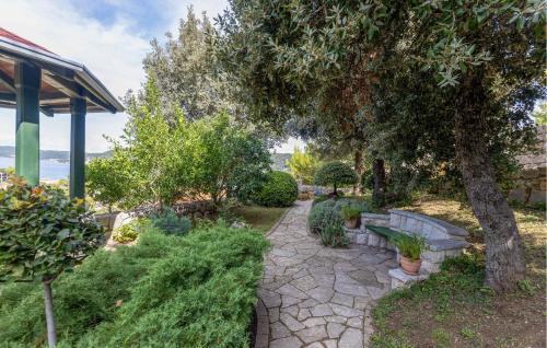 a garden with a tree and a stone path at Nice Home In Supetarska Draga With Wifi in Supetarska Draga