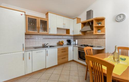 a kitchen with white cabinets and a wooden table at Nice Home In Supetarska Draga With Wifi in Supetarska Draga