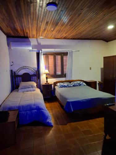 a bedroom with two beds and a wooden ceiling at Casa Encarnación in Encarnación