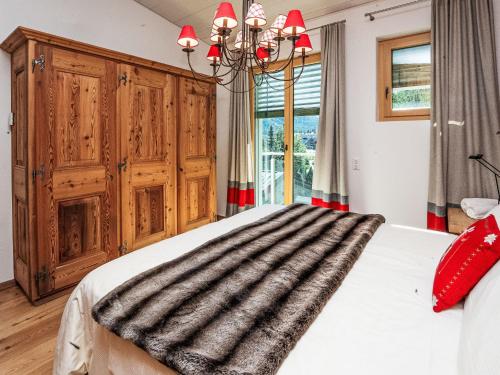 a bedroom with a large bed and a chandelier at Apartment Chesa Spuonda Verde 2-5 by Interhome in St. Moritz