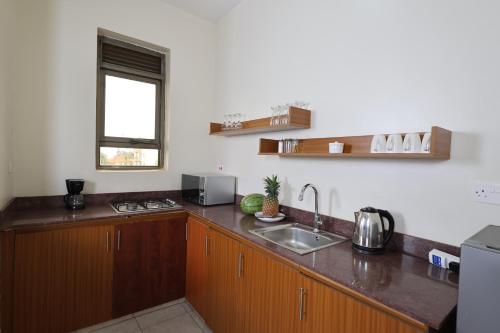 a kitchen with wooden cabinets and a sink and a window at Bon Bini Residence in Kampala