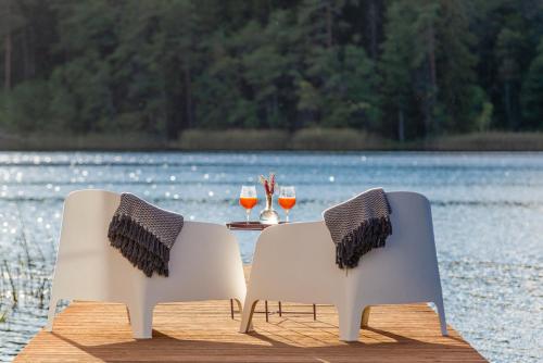 two chairs sitting next to a table with glasses of wine at Namelis ant vandens "Giliaus namelis" in Tytuvėnai