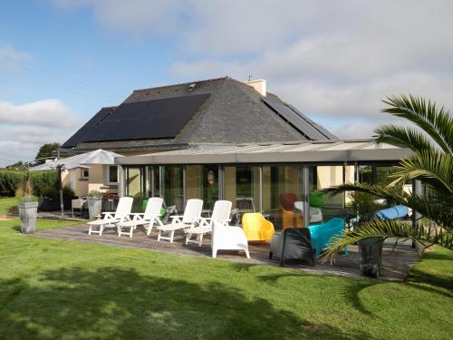 a group of white chairs and a house with solar panels at Holiday Home Chez David by Interhome in Kersaint-Plabennec
