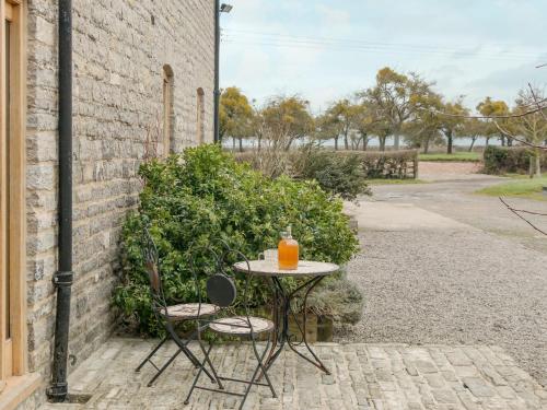 a table with an orange drink on it next to a building at Applebarn - Uk10654 in West Pennard