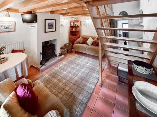 een woonkamer met een bank en een open haard bij Swinside Cottage in Ennerdale Bridge
