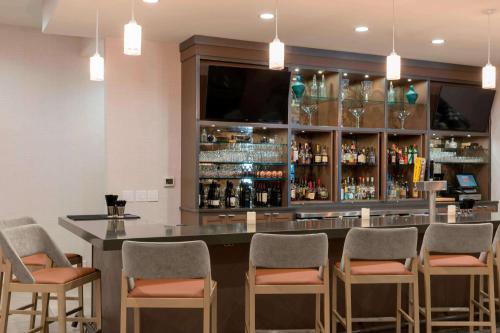 a bar with chairs and a counter with a television at Sonesta Hotel Grand Rapids Airport in Grand Rapids