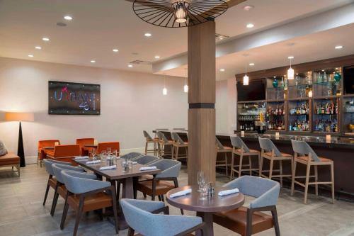a restaurant with tables and chairs and a bar at Sonesta Hotel Grand Rapids Airport in Grand Rapids