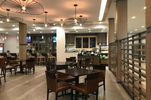 a restaurant with tables and chairs and a bar at Sonesta Hotel Grand Rapids Airport in Grand Rapids