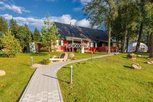 a house with a walkway in front of a yard at Namas su vaizdu į ežerą "Giliaus Nendrė" in Tytuvėnai
