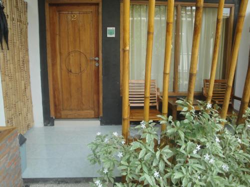 a room with a wooden door and a plant at Lara Homestay in Kuta Lombok