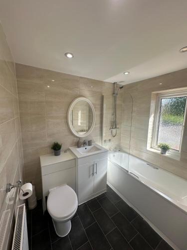 a bathroom with a toilet and a tub and a sink at Wessex House in Basingstoke