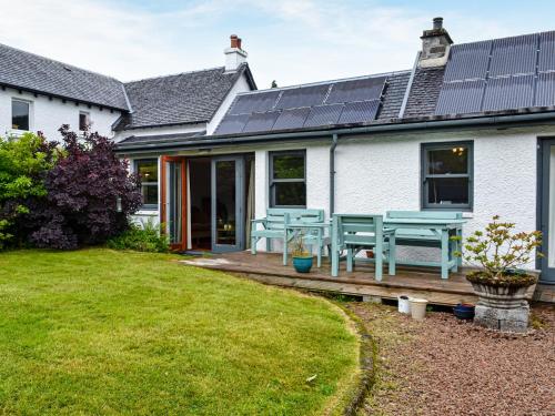 a house with a wooden deck with a picnic table at Oakwood Cottage - Glencoe in Glencoe