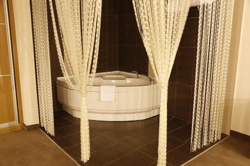 a bath tub in a bathroom with curtains at Grand Cali Hotel in Bozuyuk