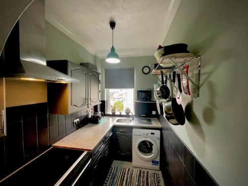 a small kitchen with a washing machine in the corner at Stylish and artistic flat in Southend on Sea in Southend-on-Sea