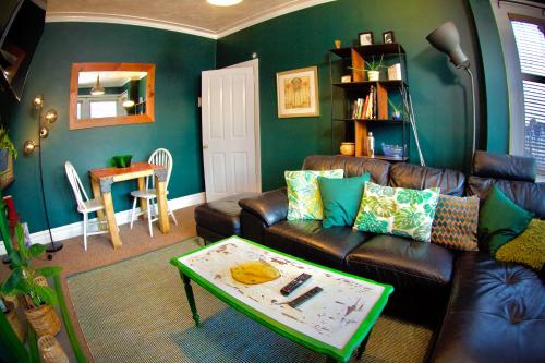 a living room with a leather couch and a table at Stylish and artistic flat in Southend on Sea in Southend-on-Sea