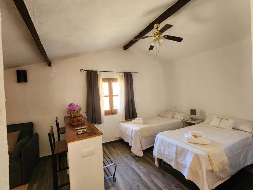 a bedroom with two beds and a ceiling fan at Casa de la luz-Finca la Sierra in Berzocana
