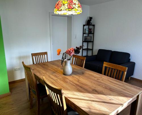 a dining room table with a vase of flowers on it at FEWO Unterm Stein - Hänsel & Gretel - 2 Schlafzimmer in Alheim