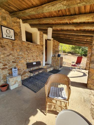 a patio with two wicker chairs and a stone wall at Casa de la luz-Finca la Sierra in Berzocana
