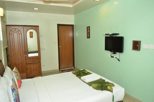 a bedroom with two beds and a tv on the wall at Athasri Hotel Cubbon Road in Bengaluru