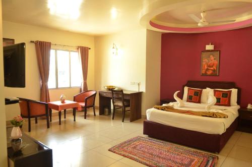 a bedroom with a bed and a table and a desk at Athasri Hotel Cubbon Road in Bengaluru