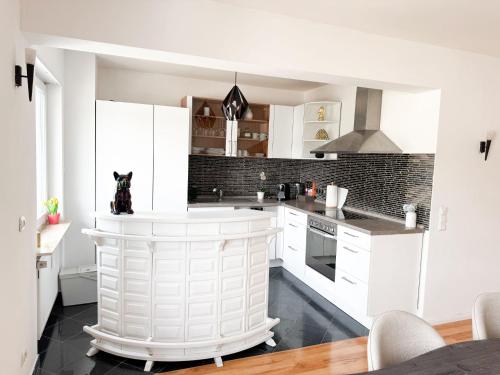 a white kitchen with a dog sitting on the counter at Appartment Wie Heim in Überherrn