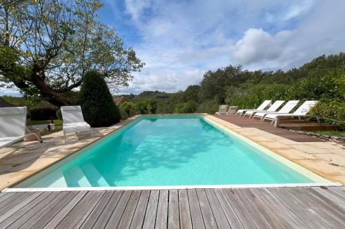 una piscina con sedie e una terrazza in legno di La longère de Sarlat a Sarlat-la-Canéda