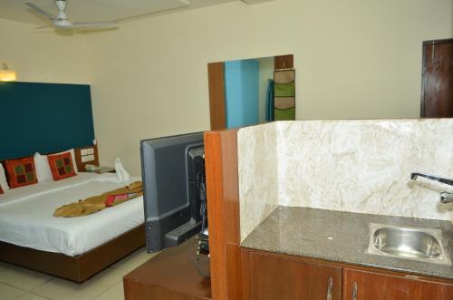 a bedroom with a bed and a sink and a tv at Athasri Hotel Cubbon Road in Bengaluru
