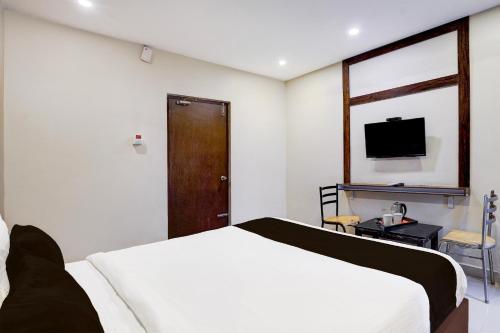 a bedroom with a white bed and a television at Super Hotel O Renigunta Near Railway Station in Tirupati