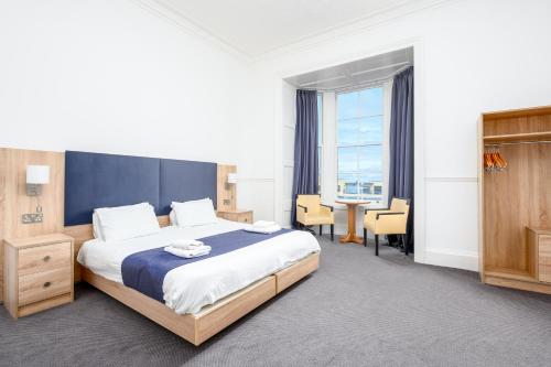 a bedroom with a bed and a table and chairs at Hotel Prince Regent in Weymouth