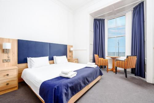 a hotel room with a bed and a desk and a window at Hotel Prince Regent in Weymouth