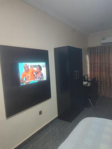 a hotel room with a flat screen tv on the wall at PollyJolly Hotel and Suites in Oba Ile
