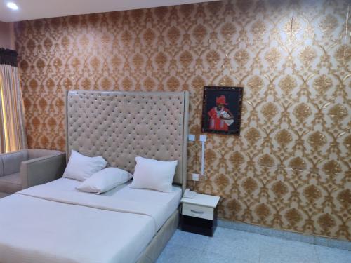 a bedroom with two beds and a wall at PollyJolly Hotel and Suites in Oba Ile