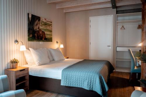 a hotel room with a bed and a blue chair at Hotel B&B Hoeve de Vredenhof in Zuidlaren