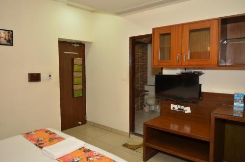 a living room with a tv and a table with a bed at Athasri Hotel Cubbon Road in Bengaluru