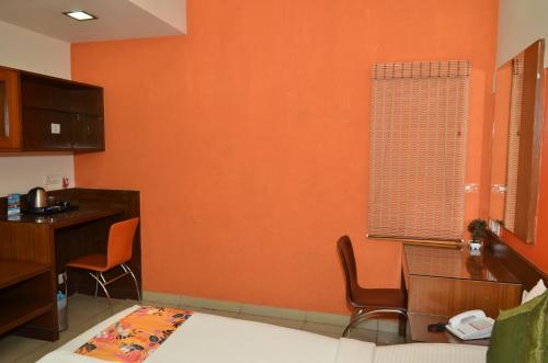 a kitchen with an orange wall with chairs and a table at Athasri Hotel Cubbon Road in Bengaluru