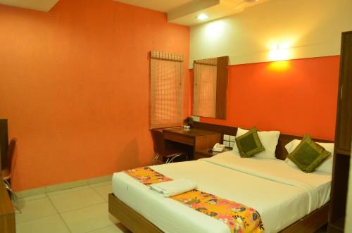 a bedroom with a bed and a desk in it at Athasri Hotel Cubbon Road in Bengaluru