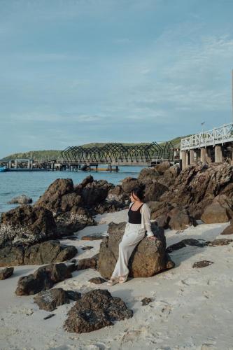 a woman sitting on a rock on the beach at Bamboo Seaview Koh Larn Second Floor - 2nd Floor in Ko Sak