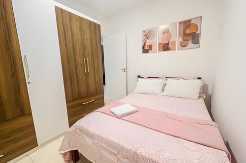 a small bedroom with a bed with a pink blanket at Ótimo apartamento, ar cond e vaga in Ourinhos