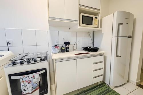 a small white kitchen with a stove and a refrigerator at Ótimo apartamento, ar cond e vaga in Ourinhos