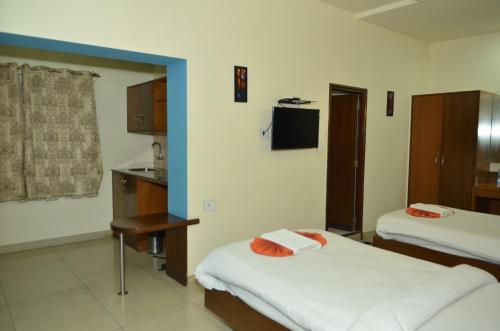 a hotel room with two beds and a kitchen at Athasri Hotel Cubbon Road in Bengaluru