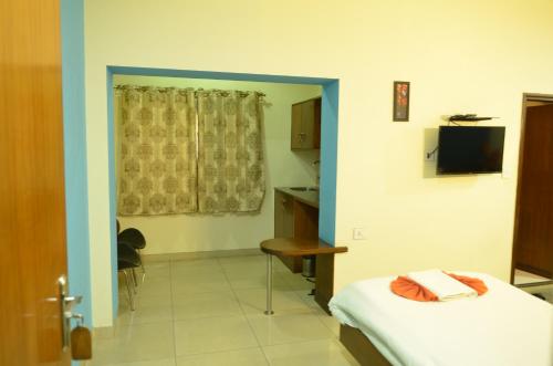 a room with a bed and a desk and a television at Athasri Hotel Cubbon Road in Bengaluru