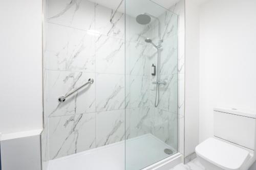 a white bathroom with a shower with a glass door at Hotel Prince Regent in Weymouth