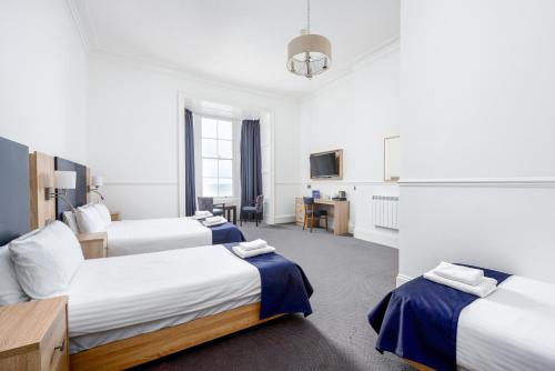 a hotel room with three beds and a tv at Hotel Prince Regent in Weymouth