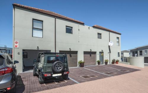 a green jeep parked in a parking lot in front of a building at Apartment 6 in Yzerfontein