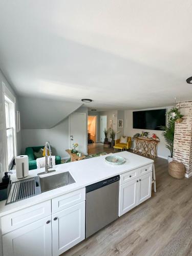 a kitchen with white cabinets and a living room at The Nest At Elm City Flats in New Haven