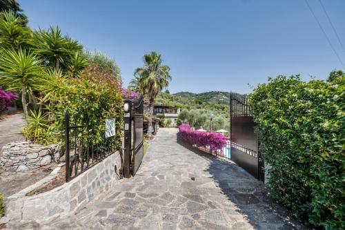 Una valla junto a una pasarela con flores moradas. en Villaré, oasi di relax nel verde della Riviera con piscina privata, en Lavagna